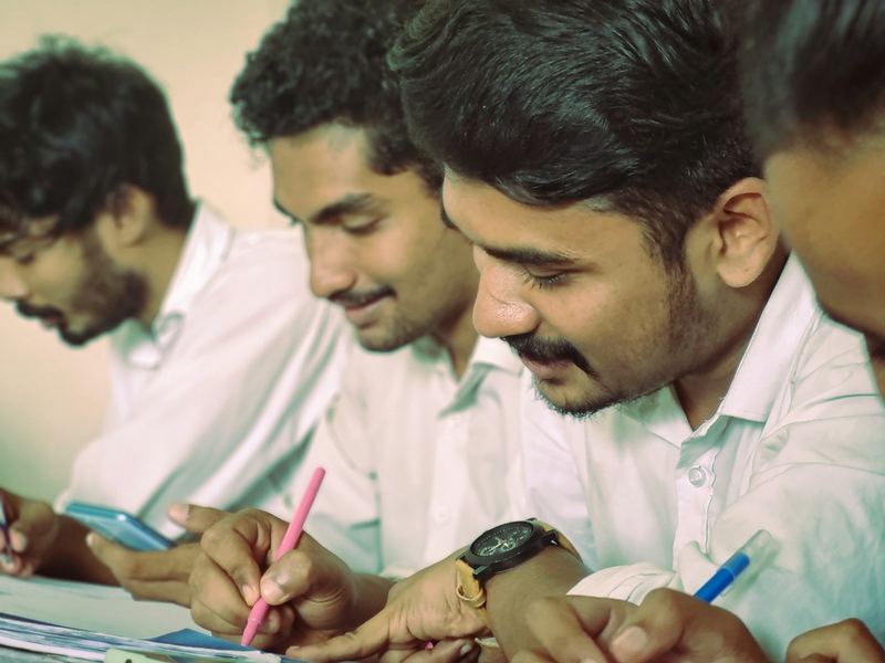 Students writing notes together at a classroom desk