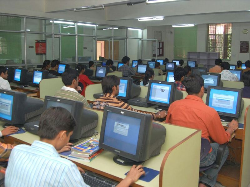 Rows of students working at desktop computers in a bright computer lab