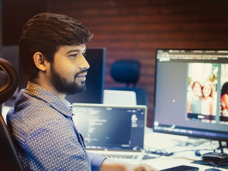 A young developer smiling while working at his computer